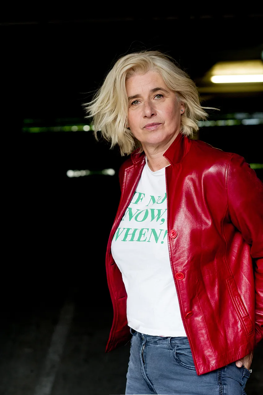 Angelika Fink in roter Lederjacke und bedrucktem Shirt in einem Gang