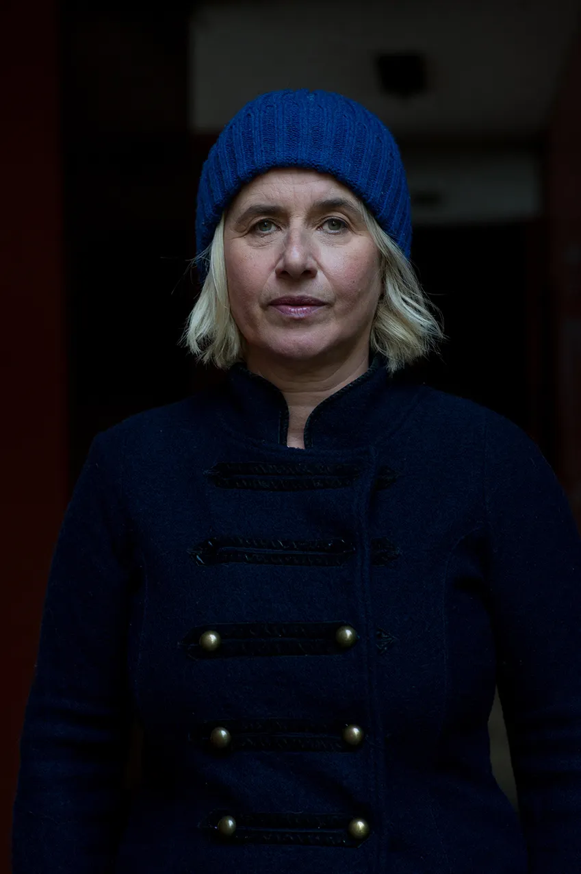 Angelika Fink mit blauer Strickmütze und dunklem Mantel im Halbdunkel